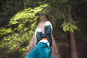 mushroom supplements for a healthier lifestyle herban shaman man on top of a tree bark in nature converse blue wearing blue jeans and orange socks